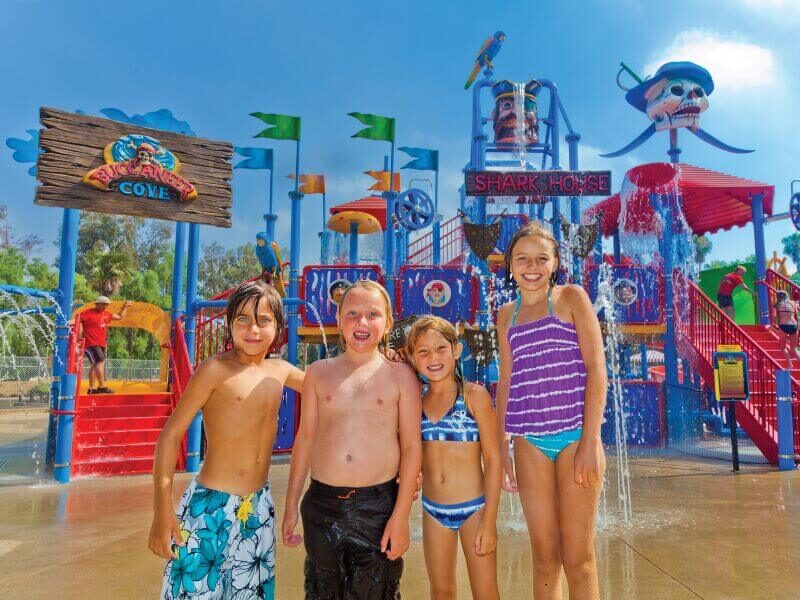 4 kids smiling in front of Buccaneer Cove